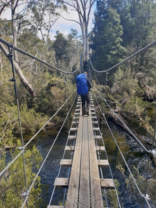 Hiker on suspension bridge wearing pack and pack cover