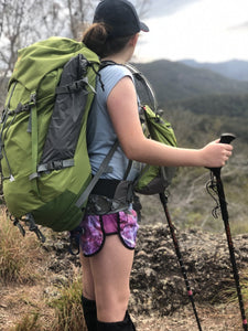 Young girl wearing Aarn backpack using walking poles