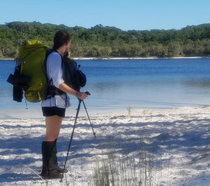 Female hiker wearing Aarn Hiking Pack with front pockets at the edge of a lake