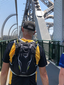 Man wearing Osprey Men's Duro 6 Race Vest Pack walking on bridge