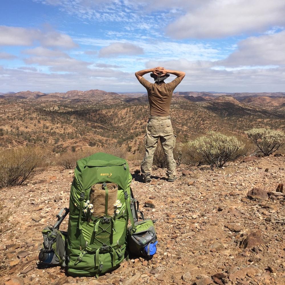 Man looking out over the South Australian desert with his Aarn hiking pack in the foreground