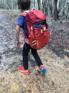 Young male wearing Osprey Jet 18 Pack hiking on dirt trail